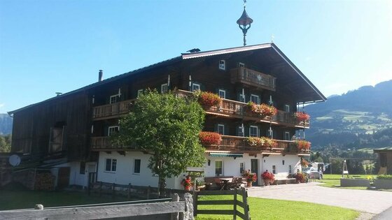Sommer Ansicht Angererhof Traditionelles Holzhaus mit Blumenschmuck auf den Balkonen vor Bergkulisse.