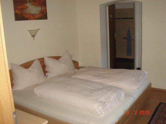 Schlafzimmer Appartement Neuhaus Doppelbett mit weißer Bettwäsche in einem hellen Zimmer mit Blick ins Bad.