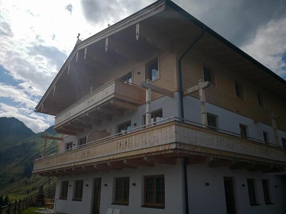 Chalet Rettenstein & Bärenbadkogel Mehrstöckiges alpines Gebäude mit Holzbalkonen vor einer Bergkulisse unter bewölktem Himmel.