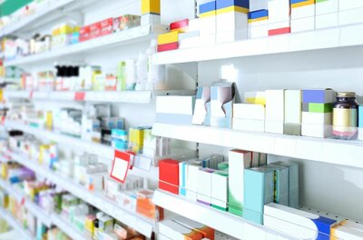 Regale mit Medikamenten Weiße Regale in einer Apotheke oder Drogerie mit verschiedenen Medikamentenpackungen.