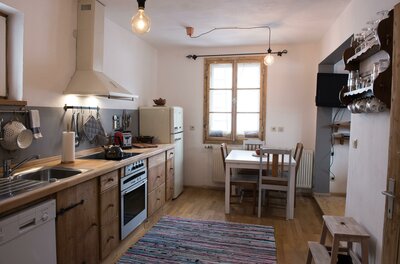 Küche mit Holzfronten, Elektrogeräten, Esstisch und Fenster in einer Ferienwohnung.