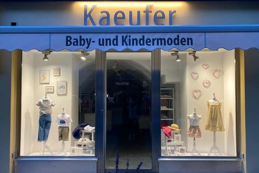 Kaeufer Baby- und Kindermoden Schaufenster des Geschäfts Kaeufer Baby- und Kindermoden mit ausgestellter Kinderkleidung auf Mannequins.