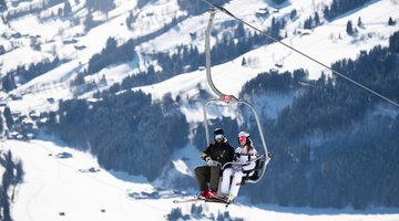 Couple takes a 2-seater chairlift to Bichlalm for skiing