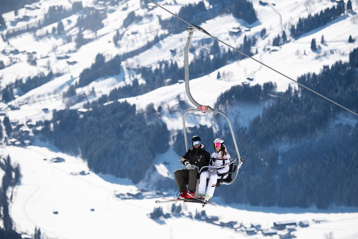 Couple takes a 2-seater chairlift to Bichlalm for skiing