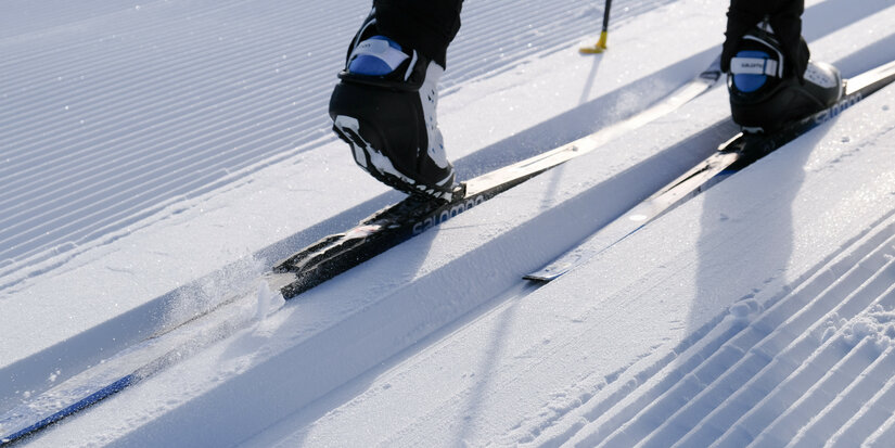 During a cross-country skiing event in Kitzbühel, a skier glides along a freshly groomed trail in bright sunshine.