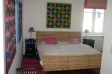 Schlafzimmer im Orsini-Rosenberg Schlafzimmer mit Doppelbett aus Korbgeflecht, Nachttischen und bunten Wandbildern.