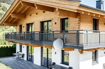 Zweistöckiges Ferienhaus aus Holz und weißem Putz mit großem Balkon und Terrasse.