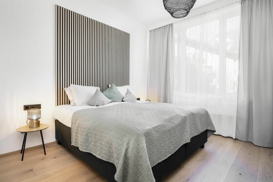Modernes Doppelbett mit gestreiftem Wandpaneel aus Holz, Nachttisch und großem Fenster.