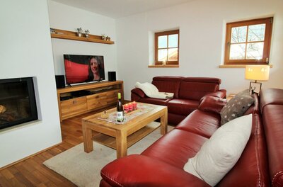 Wohnzimmer mit roter Ledercouch, Holztisch, Fernseher und Kamin.