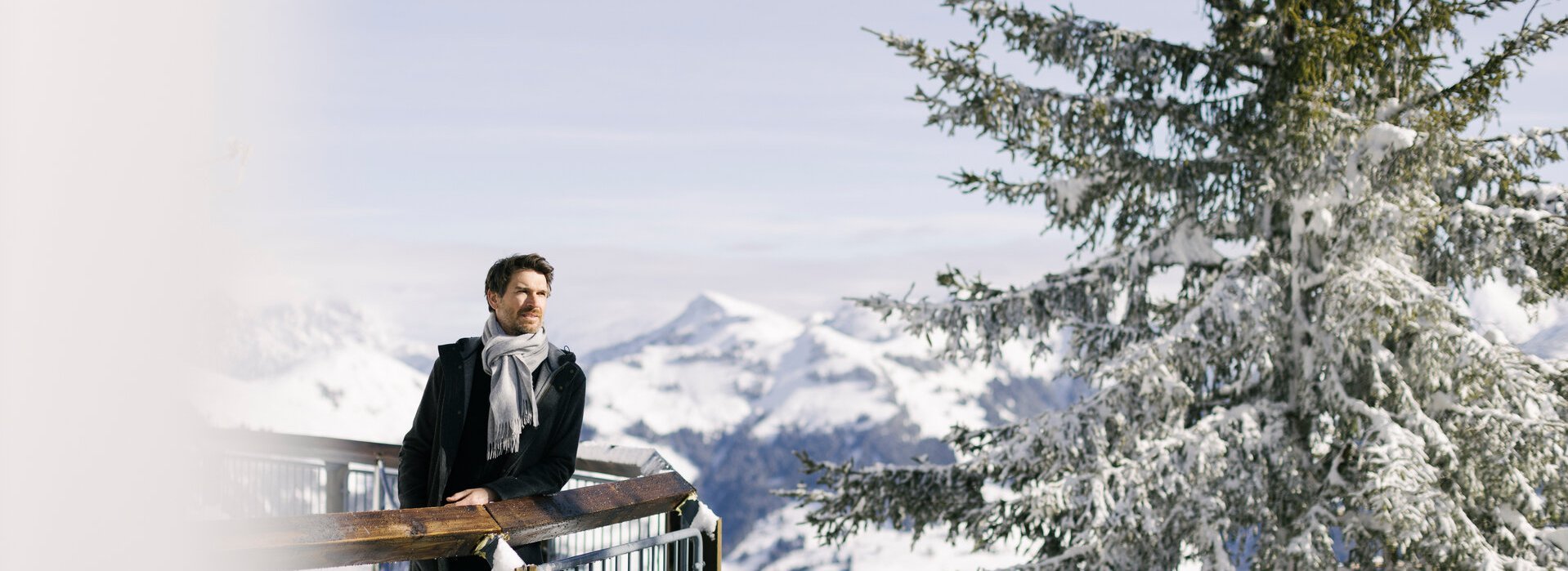 Ein Herr genießt die Aussicht auf die Berg-Winterlandschaft am Hahnenkamm an einem sonnigen Tag