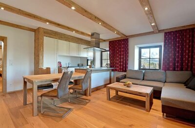Wohnzimmer-Küche im Pöllhof Moderner Wohn- und Essbereich mit Holzboden, Holzbalkendecke, Ecksofa und offener Küche.