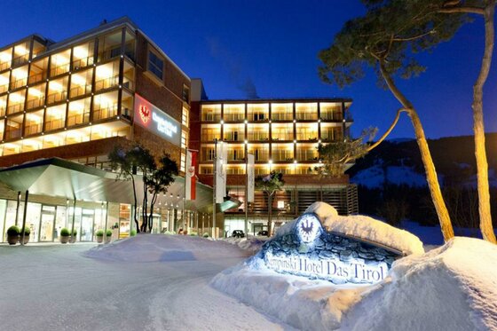 Beleuchtete Außenansicht des Kempinski Hotels Das Tirol bei Nacht mit verschneiter Einfahrt.