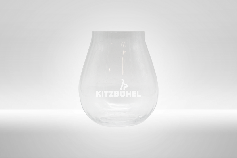 Ein elegantes, transparentes Glas mit dem Schriftzug 'KITZBÜHEL' auf der Vorderseite, vor einem hellen Hintergrund.