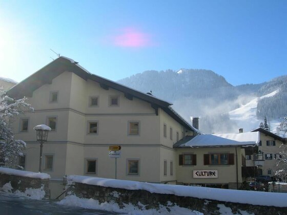 Mehrstöckiges Gebäude mit Schneebedeckung vor bewaldeten Bergen im Winter.