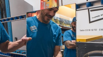 Zwei Männer in der Glaserwerkstatt vor einem Spiegel