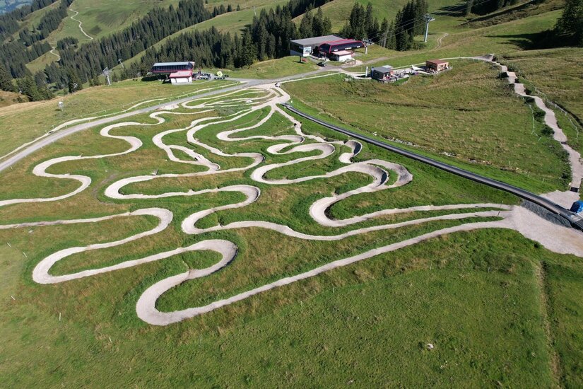 Family Area Streiteck Luftaufnahme eines Mountainbike-Übungsgeländes mit vielen Kurven auf einer grünen Bergwiese.