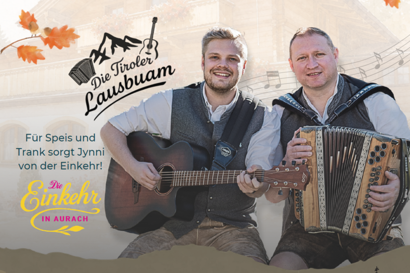 Zwei Musiker in Tracht mit Gitarre und Harmonika vor einem Holzhaus.