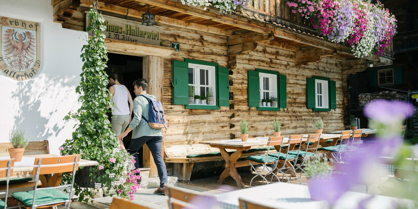 Ein traditionelles Gasthaus in den Alpen, geschmückt mit Blumen, während Gäste die einladende Atmosphäre genießen.