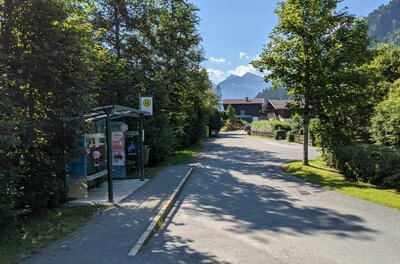 Bushaltestelle Staudach Bushaltestelle mit Wartehäuschen an einer asphaltierten Straße in Staudach vor Bergkulisse.