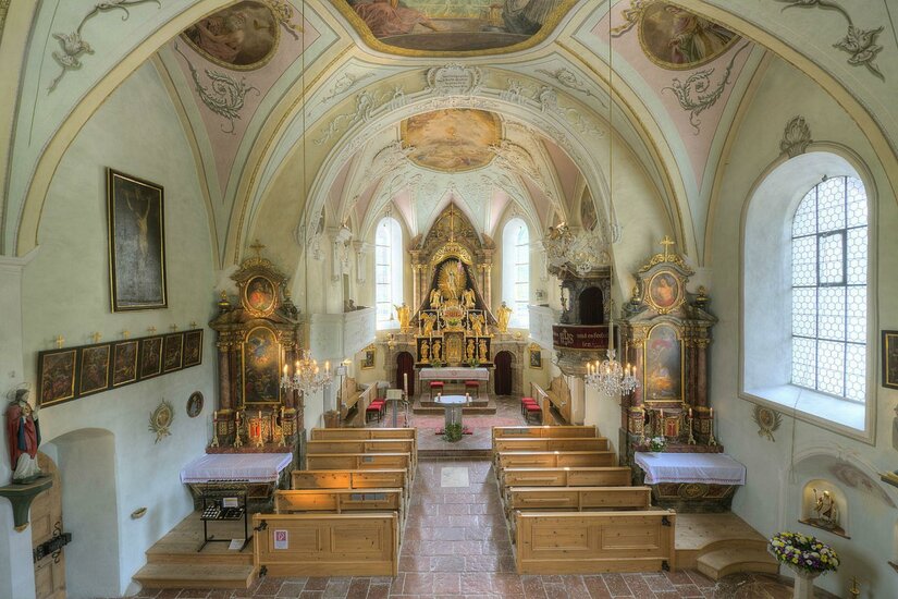 Pfarrkirche Aurach Winter Eine schöne Kirche mit einem beeindruckenden Altar und kunstvollen Deckenmalereien. Die Holzbänke bieten Platz für die Besucher.