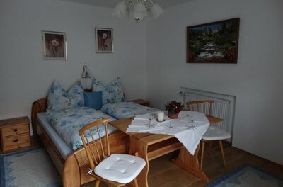 Schlafzimmer im Haus Alpenrose Schlafzimmer mit Doppelbett aus Holz, einem kleinen Esstisch und zwei Stühlen.