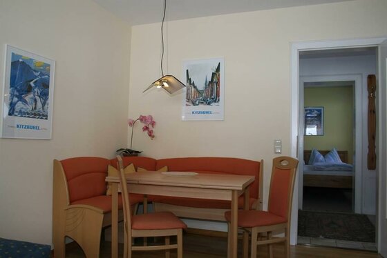 Essecke im Haus Sandra Essecke mit Holztisch, orangefarbener Eckbank und zwei Stühlen in einer Ferienwohnung.