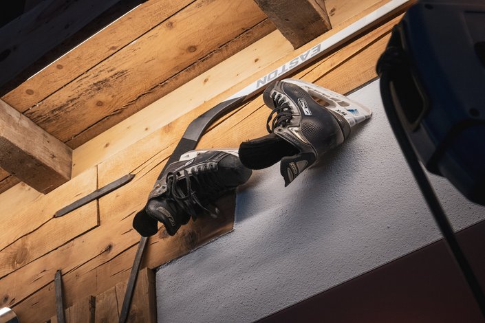 Eislaufschuhe und ein Hockeyschläger hängen an der Wand
