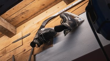 Eislaufschuhe und ein Hockeyschläger hängen an der Wand
