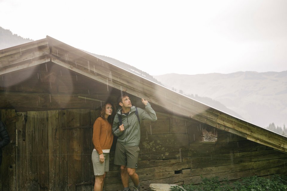 Paar unter Hüttendach bei Regen