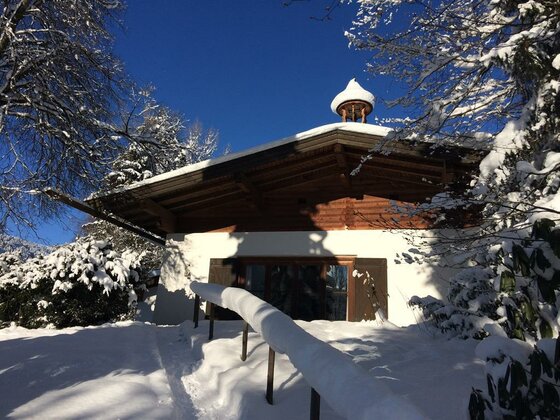 Winterliches Haus in Lutzenberg Verschneites Holzhaus mit weißer Fassade und Glockenturm unter blauem Himmel.