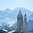 Die idyllische Winterlandschaft zeigt eine charmante Stadt mit Kirchen und schneebedeckten Bäumen, umgeben von majestätischen Alpen.