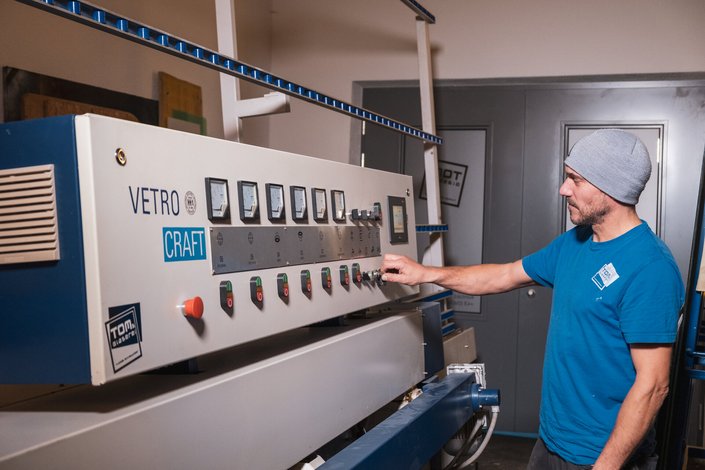 Ein Mann bedient eine Maschine in einer Glaserei