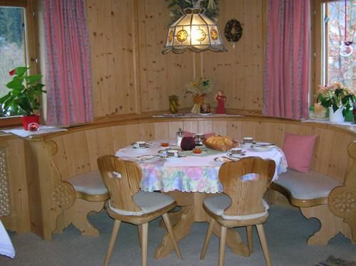 Frühstücksraum Haus Filzer Rustikale Sitzecke aus hellem Holz mit rundem, gedecktem Tisch und Eckbank.