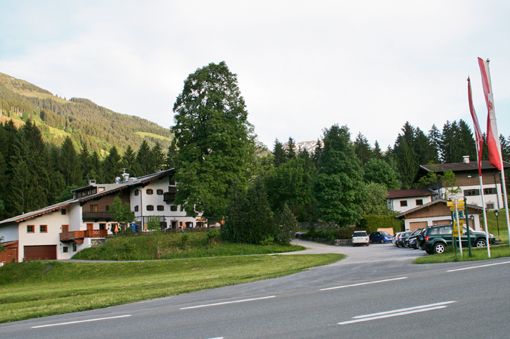 Gasthof Jodlbühel Außenansicht Außenansicht des Gasthofs Jodlbühel mit Parkplatz und bewaldetem Berghang im Hintergrund.