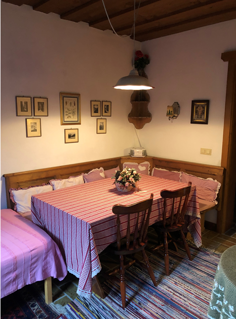 Essbereich Chalet Marie-Luise Rustikaler Essbereich mit Eckbank aus Holz, karierter Tischdecke und hängender Lampe.