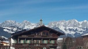 Hölzlhof-Vermietung-Bauernhof-Kitzbühel-Winter Ein traditionelles Chalet vor majestätischen Bergen. Der klare Himmel und die schneebedeckten Gipfel schaffen eine malerische Alpenlandschaft.