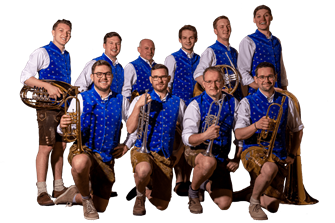 Oberwachauer Eine Musikergruppe steht in traditioneller Tracht. Sie tragen blaue Westen und halten Instrumente in der Hand.