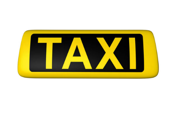 Gelbes Taxi-Schild mit schwarzer Aufschrift vor weißem Hintergrund.