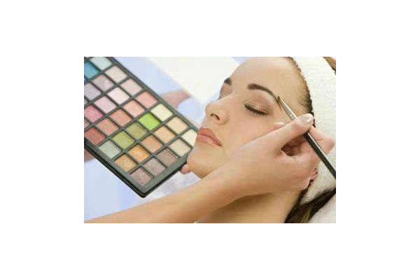 Eine Frau erhält ein professionelles Augenbrauen-Make-up mit Pinsel und Lidschattenpalette.