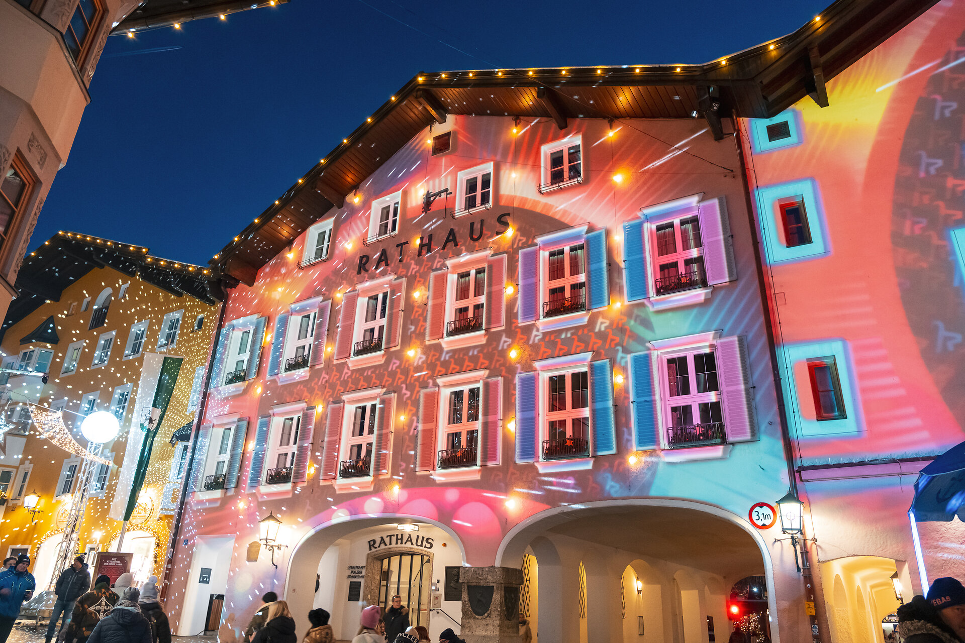 Die Fassade des Rathauses in Kitzbühel erstrahlt in bunten Lichtern und Projektionen während einer festlichen Veranstaltung.