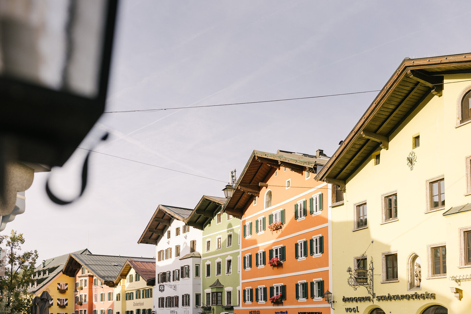 Bunte Fassaden von Gebäuden in einer malerischen Stadt, die im Herbstlicht erstrahlen und eine einladende Atmosphäre schaffen.
